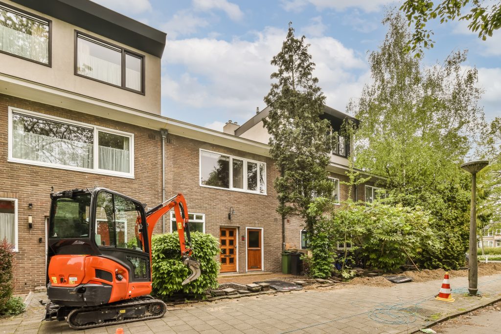 a construction machine parked in front of a brick house